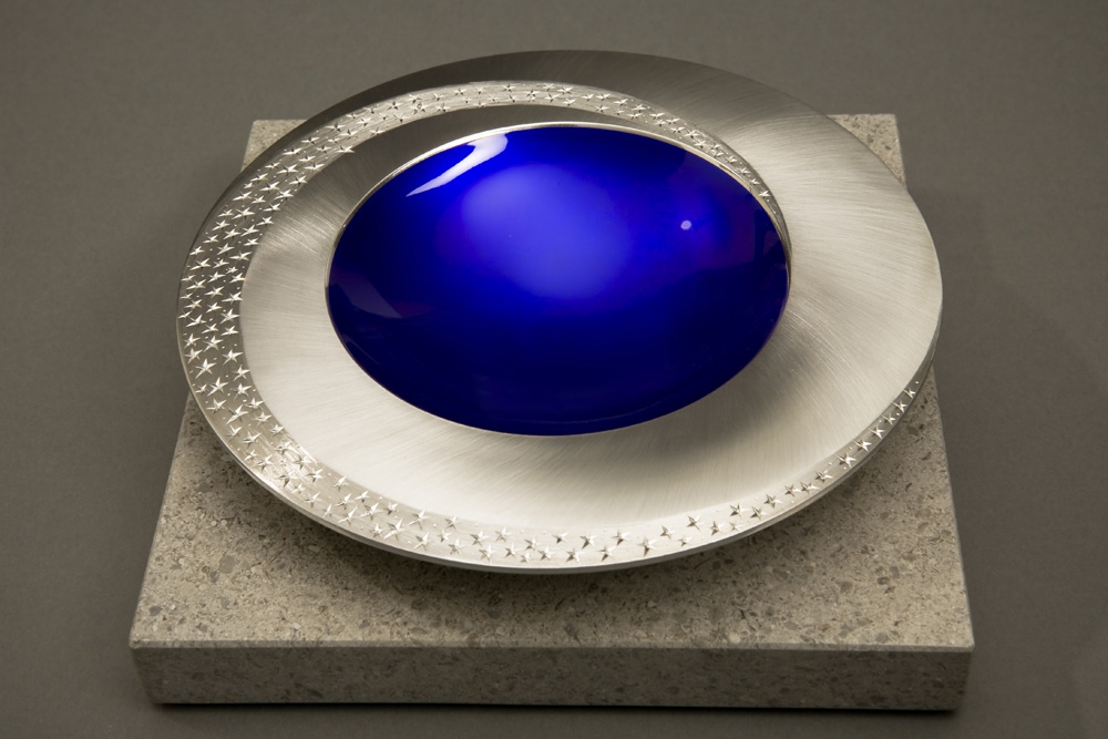 <a href="/jewellery/angle-view-starlight-bowl-150-mm-diameter-britannia-silver-blue-enamel-hand-engraved">Angle view: STARLIGHT BOWL 150 mm diameter. Britannia Silver. Blue Enamel, Hand Engraved. Brushed and striated finish. Base polished Limestone. Bowl is designed to spin gently on its stone base. Photo : Simon Armitt</a>